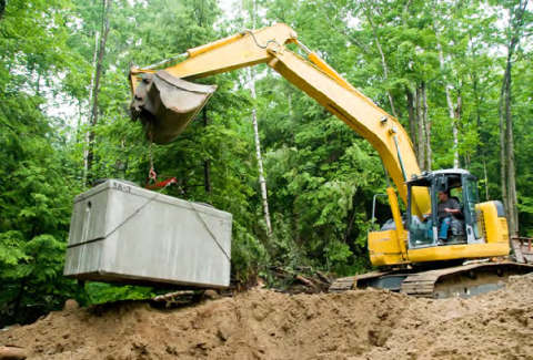 backhoe lowering a septic tank