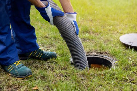 Maintenance Worker emptying household septic tank. 